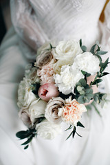 Bride holding in hands a wedding bouquet of pastel flowers, vintage style, blurred background