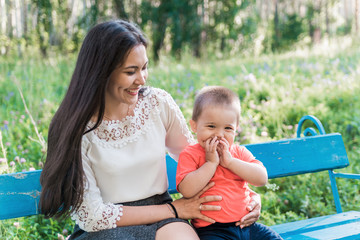 A happy young mother plays and has fun with her young son in nature, in the Park. The mother is...