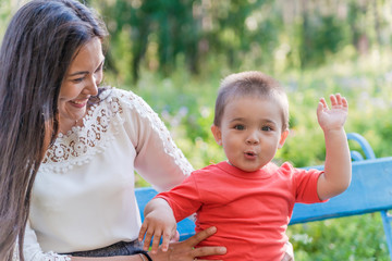  A happy young mother plays and has fun with her little son in the sun on a warm spring or summer...