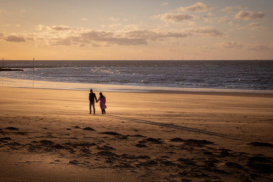 couple walking on the beach in Margate at sunset