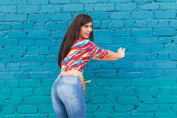 Street shaabi dance and urban dancer concept - Cheerful belly dancer dancing with arabic music on the street, blue brick wall background with copy space