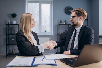 Group of two business partners in formal suits shaking hands to celebrate successful conclusion of negotiations. Concept of teamwork and gesture meaning