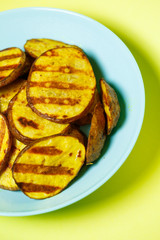 grilled potatoes until golden brown in a blue plate on a yellow background