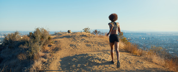 fit african american woman running at runyon canyon with los angeles in background
