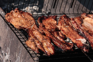 A large steak of grilled meat with smoke. Cooking in the open air.