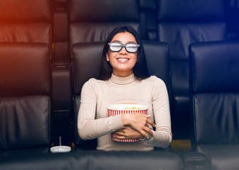 Asian girl in 3D glasses enjoying interesting film in cinema