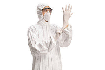 Man in a white decontamination suit putting on medical gloves