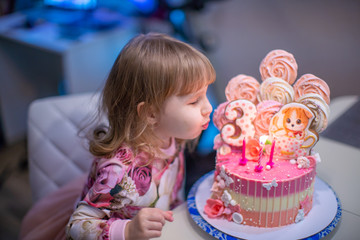 Birthday. A happy little girl blows out the candles on the birthday cake.