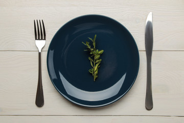 Table setting. Blue plate and Cutlery, fork and knife on a white wooden table. top view