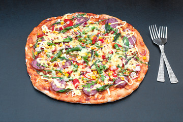 Hot homemade pizza with cutlery fork and knife, black background