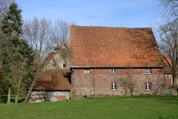 Altes Bauernhaus im Sonnenschein mit grüner Wiese im Winter auf einem Bauernhof und Gehöft in...