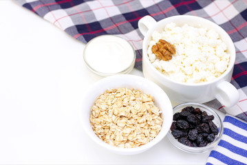 Breakfast concept. cottage cheese with walnuts, oatmeal, raisins and sour cream on a light background and a towel. white