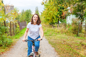 Naklejka premium Young woman riding bicycle in summer city park outdoors. Active people. Hipster girl relax and rider bike. Cycling to work at summer day. Bicycle and ecology lifestyle concept.
