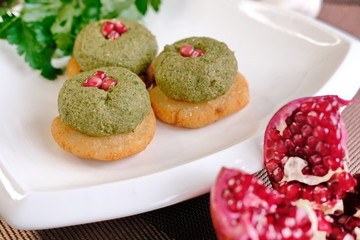 Green bean pkhali on corn tortilla mchadi on a white plate, a traditional Georgian dish of vegetables ,walnuts, garnished with pomegranate