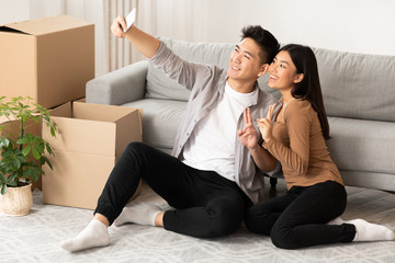 Asian man and woman taking selfie sitting on the floor