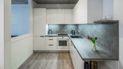 Modern interior of kitchen in private house. Clean white kitchen set. Flowers.