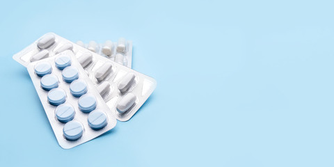 Pills in blister packs on blue background. Medicine concept.