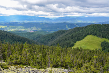 Obraz premium Landscape view on the beautiful Carpathian mountains on the High Top near the Bukovel ski resort village against a cloudy sky. Ukraine