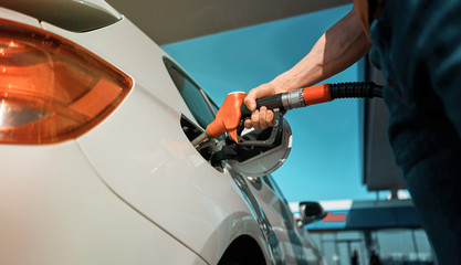 man refuels a car at a gas station
