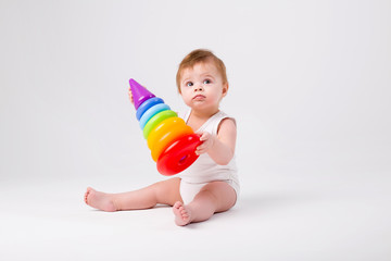 healthy baby girl sitting playing with an educational toy on a white background isolate