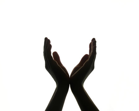 the two hands are joined, and the palms of the hands are open, as if holding something. dark hands silhouetted against a white background. the palms form the letter V. hands hold the ball.