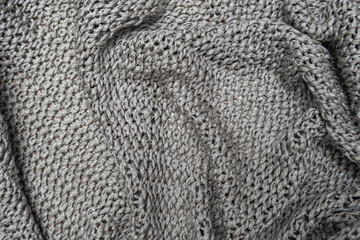 Crumpled folded beige, brown knitted fabric background, woolen knitwear plaid close up