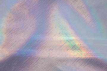 Photo of a real bright rainbow crumpled holographic background with a skin texture with rays...