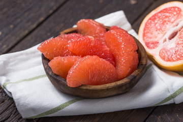 Fresh grapefruit slices in a wooden bowl, healthy snack