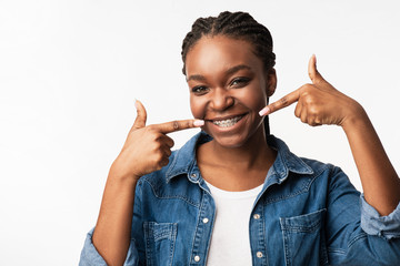 Young African Woman Pointing Fingers At Braces Standing In Studio