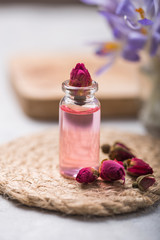 Obraz na płótnie Canvas Natural pure rose oil or scented water in bottles for spa, skin care or aromatherapy with pink roses dry. Organic cosmetics concept. Selective focus