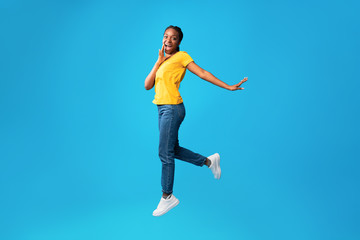 Fototapeta na wymiar Cheerful Woman Shouting Jumping In Air On Blue Background