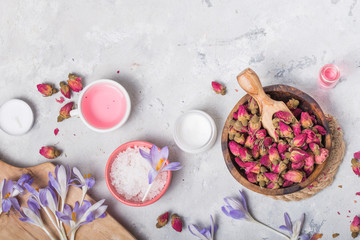 Spa and wellness concept with sea salt, dry roses, brush, oil and towel on grey  background, banner, copy space, top view