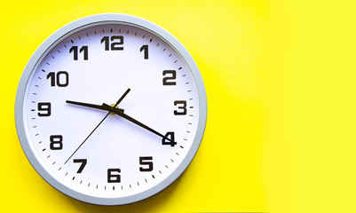 Analog white clock on a yellow background. Large numbers and arrows. Clock in close-up. Place for text.  Business, are you ready?