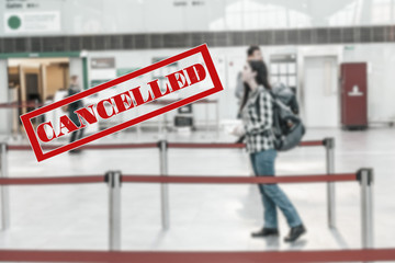 A woman stands with a backpack in airport, waiting for the plane to take off. Blurred. Cancelled sign.The concept of a ban on flights, closure of state borders and a virus pandemic