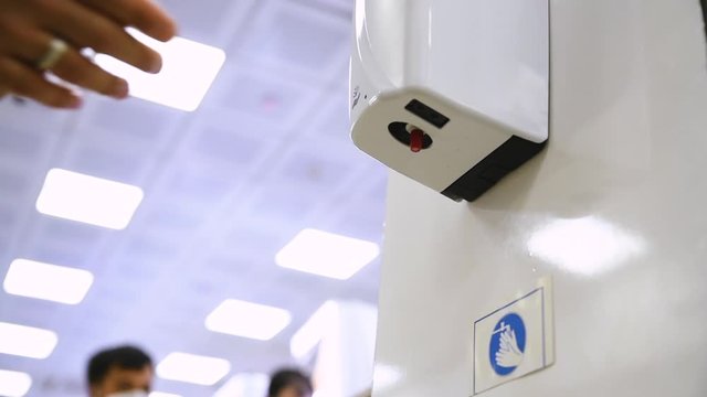 Hand sanitizer in market. People sanitize their hands before shopping