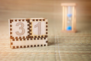 Calendar, wooden cube with date 31 and an empty space for the month, on an abstract woven hourglass...