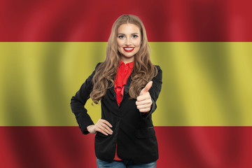 Spain. Happy student girl with thumb up against the spanish flag