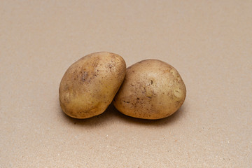 Fototapeta premium raw dirty potatoes on a craft color background