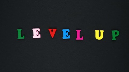 Word "level up" formed of wooden multicolored letters. Colorful words loop. - Powered by Adobe