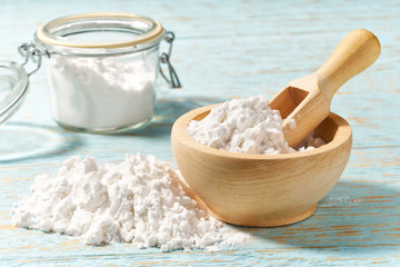 Wooden bowl with corn starch close-up  on a wooden table.