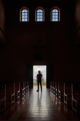 Silhouette of a mans standing at the church entrance, dark, unrecognizable interior