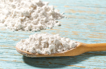 Potato starch in wooden spoon with  blue wooden table.