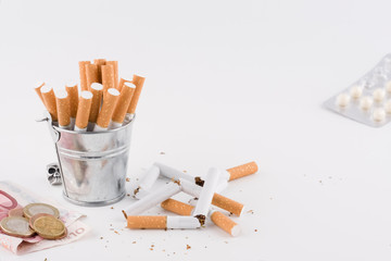 money and medicine next to a bucket of cigarettes