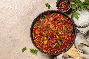 Chili con carne in skillet on light stone table.