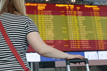 Fototapeta na wymiar Woman looks at the scoreboard at the airport. Select a country Spain for travel or migration.