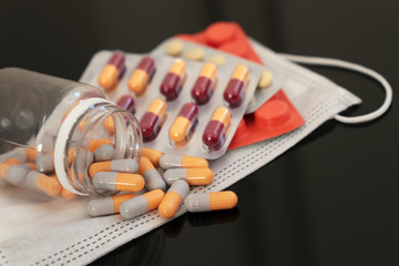 Medications in tablets and capsules on a medical face mask. Protection and profilactic of COVID-19 coronavirus pandemic
