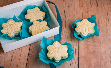 Shortbread cookies with meringue in the form of a flower, on a light wood background.