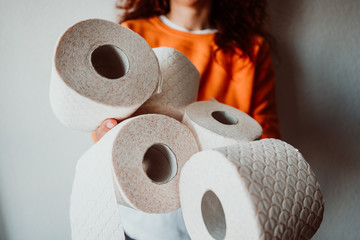 .Young woman hoarding a lot of toilet paper at home. Madness caused by the coronavirus health crisis.