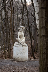 Statue of a seated half-naked woman in a park