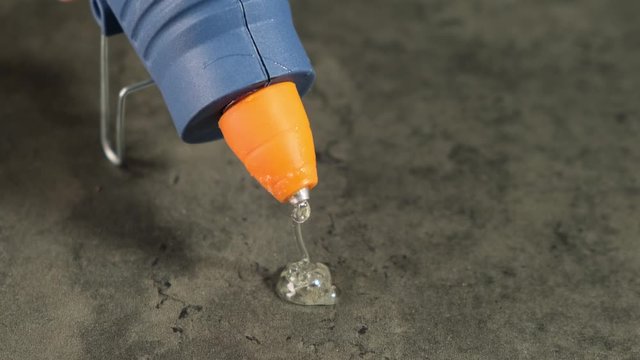 Glue gun drips onto the table. Close up.